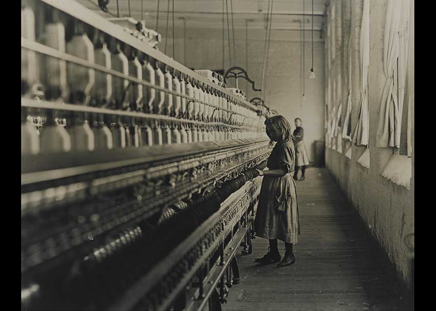 LIttle girl working at a bobbin michine at a mill