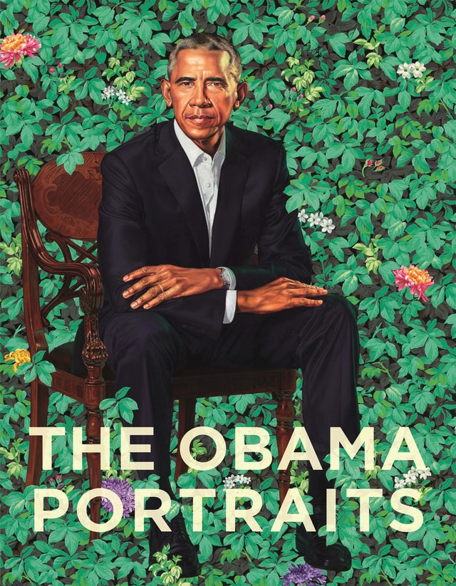 full length portrait of a man in a suit sitting amongst greenery