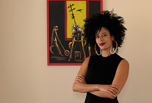 Young Black woman with large earrings standing in front of a painting