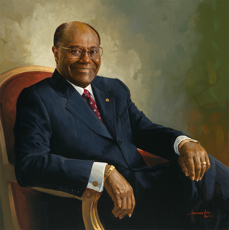 African American man in a dark suit seated in a red chair