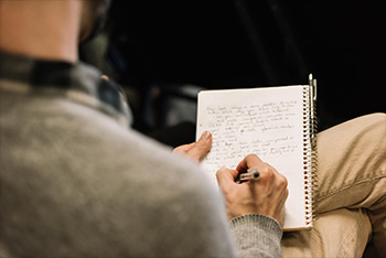 Man with a small notebook writing on his lap