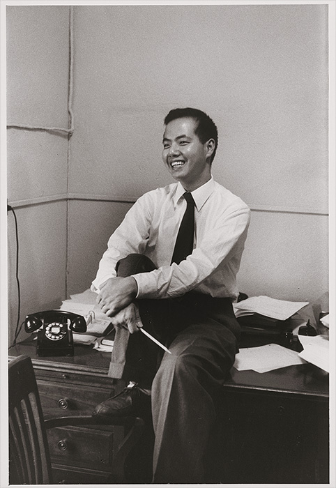 Young Asian man in a white shirt and tie sitting on his desk